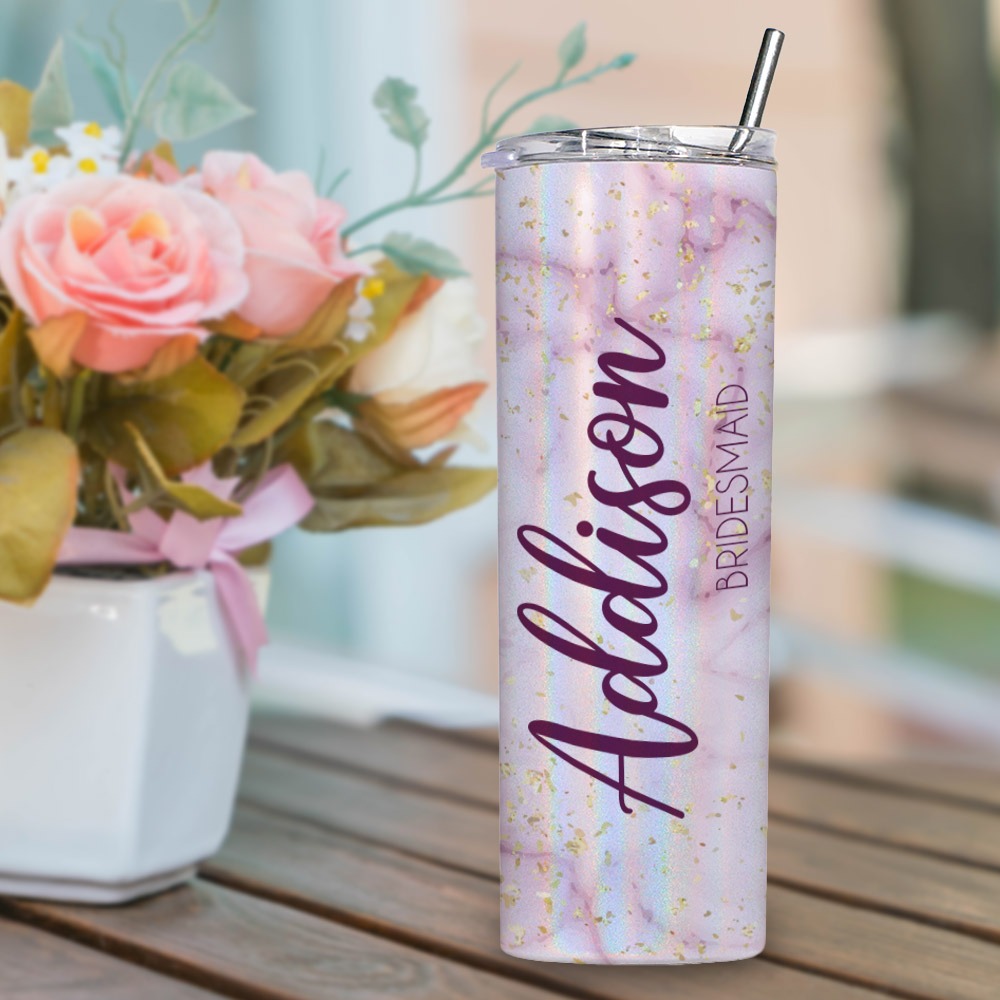 Shimmer skinny tumbler customized with name and bridesmaid, displayed near a flower arrangement