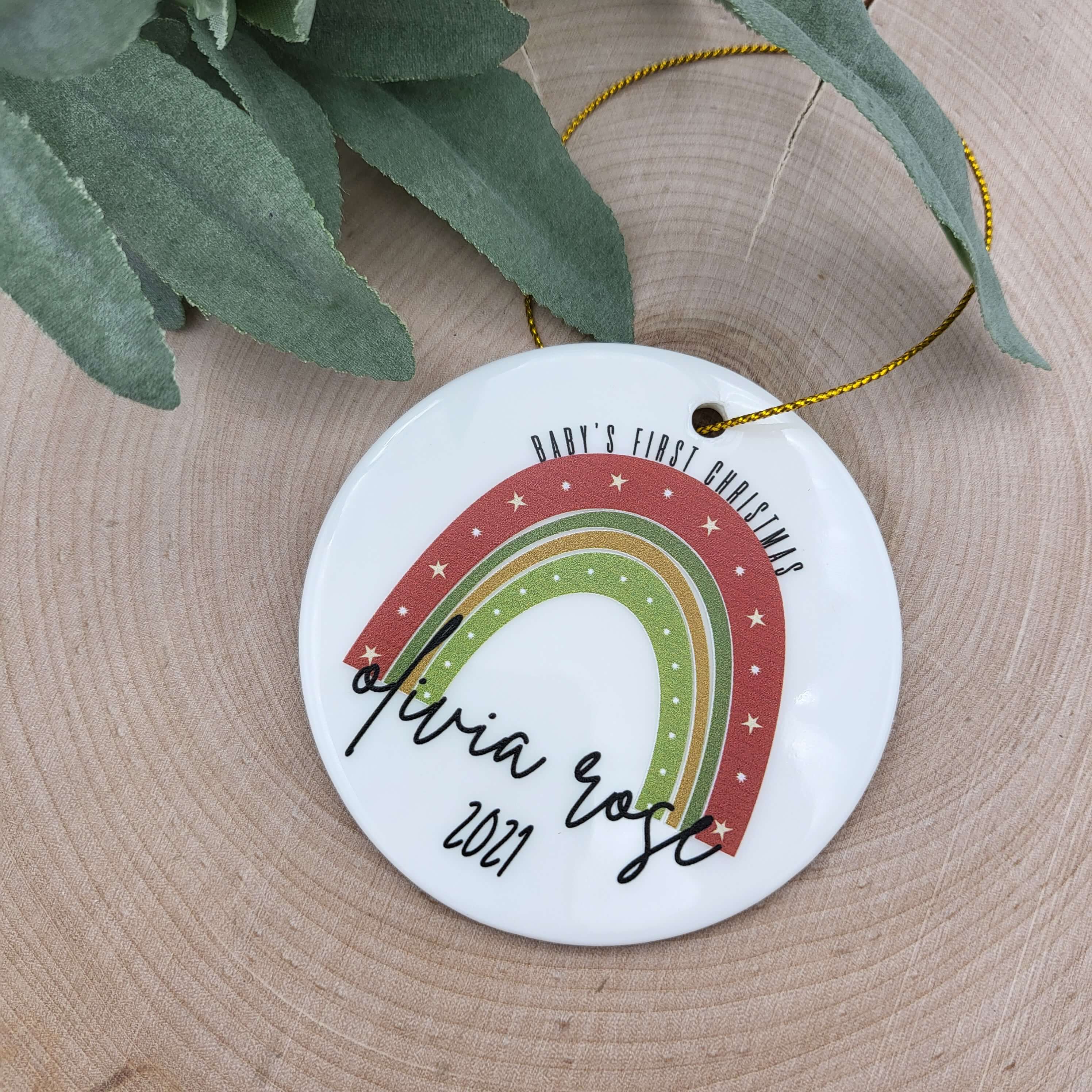 Ceramic round ornament personalized with a rainbow, "Baby's First Christmas", name and year