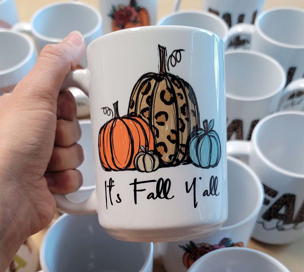 Coffee cup personalized with "It's Fall Y'all" and an assortment of pumpkin images