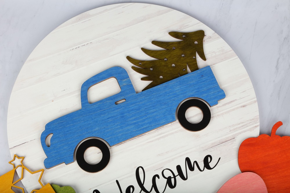 Round wooden sign with truck hauling a pine tree on it
