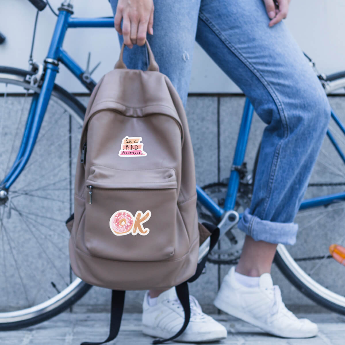 person standing by a bicycle holding a customized backpack