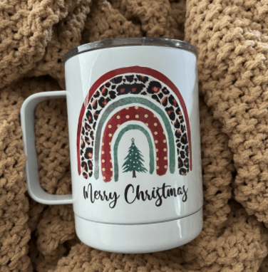 Coffee cup personalized with "Merry Christmas" under a tree and archway